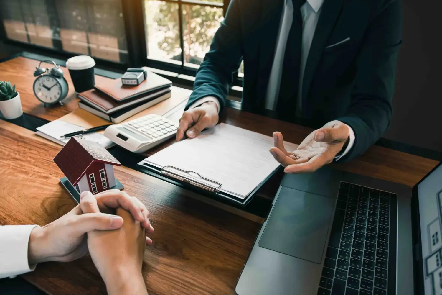 Versicherungsmakler zeigen Kunden im Büro auf den Abschluss eines Versicherungsvertrags und erklären ihnen die Details.